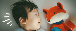 A stylized photo of a baby with a stuffed fox toy.