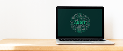 A laptop showing a graphic with the word "Audit" in the middle.