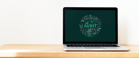 A laptop showing a graphic with the word "Audit" in the middle.